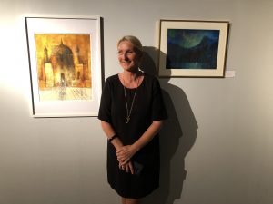 Ellen Hegg foran to av sine bilder som man finner på utstillingen